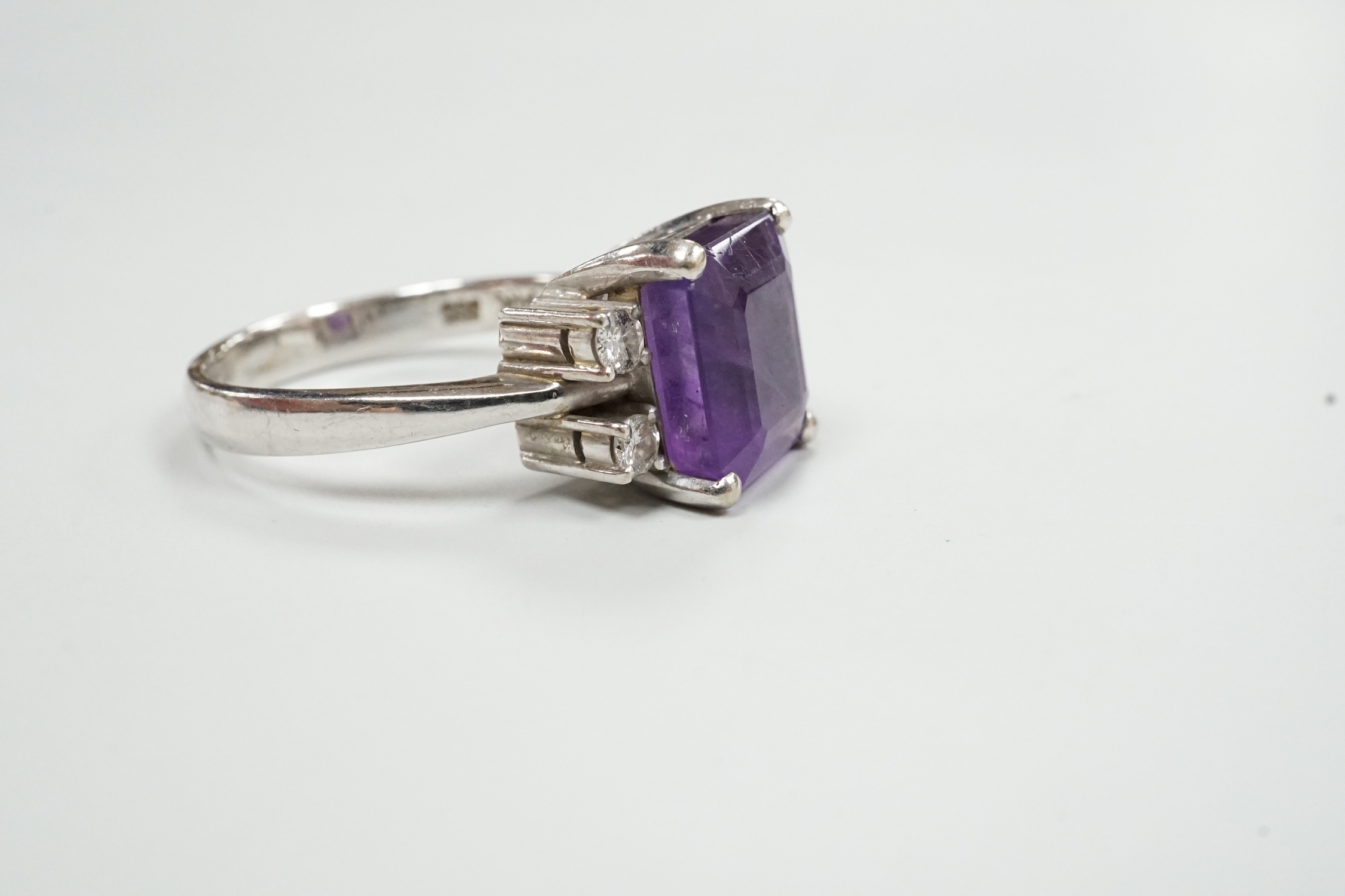 A modern 585 white metal single stone amethyst and four stone diamond set dress ring, size S/T, gross weight 8.1 grams.